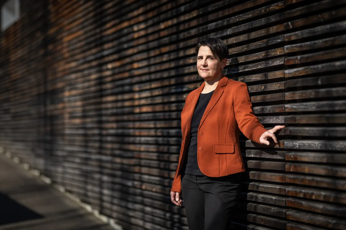 Am Vormittag war sie als neue Nationalrätin noch in Bern. Am Abend hatte Yvonne Bürgin (Die Mitte) die Gemeindeversammlung zu leiten. (Archiv) Eine Frau im orangen Blazer steht vor einer Holzwand.